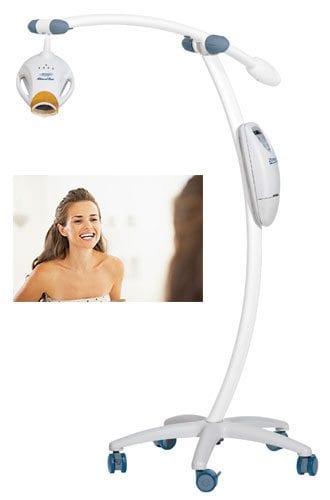 A smiling woman seeing her teeth on the mirror and teeth whitening machine