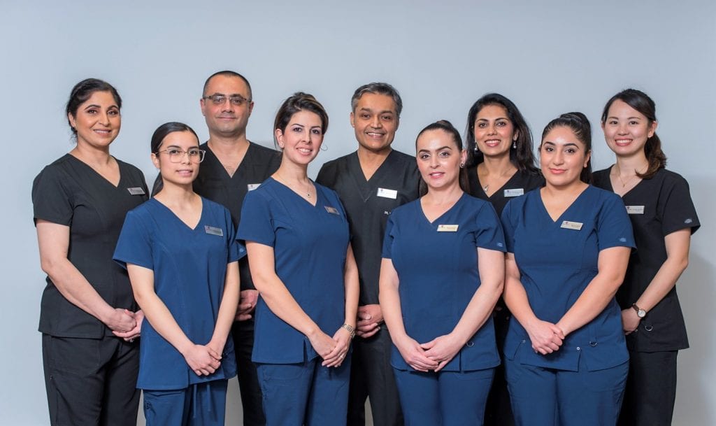 Group photo of dentists, managers and assistances with their uniforms and sky blue background behind